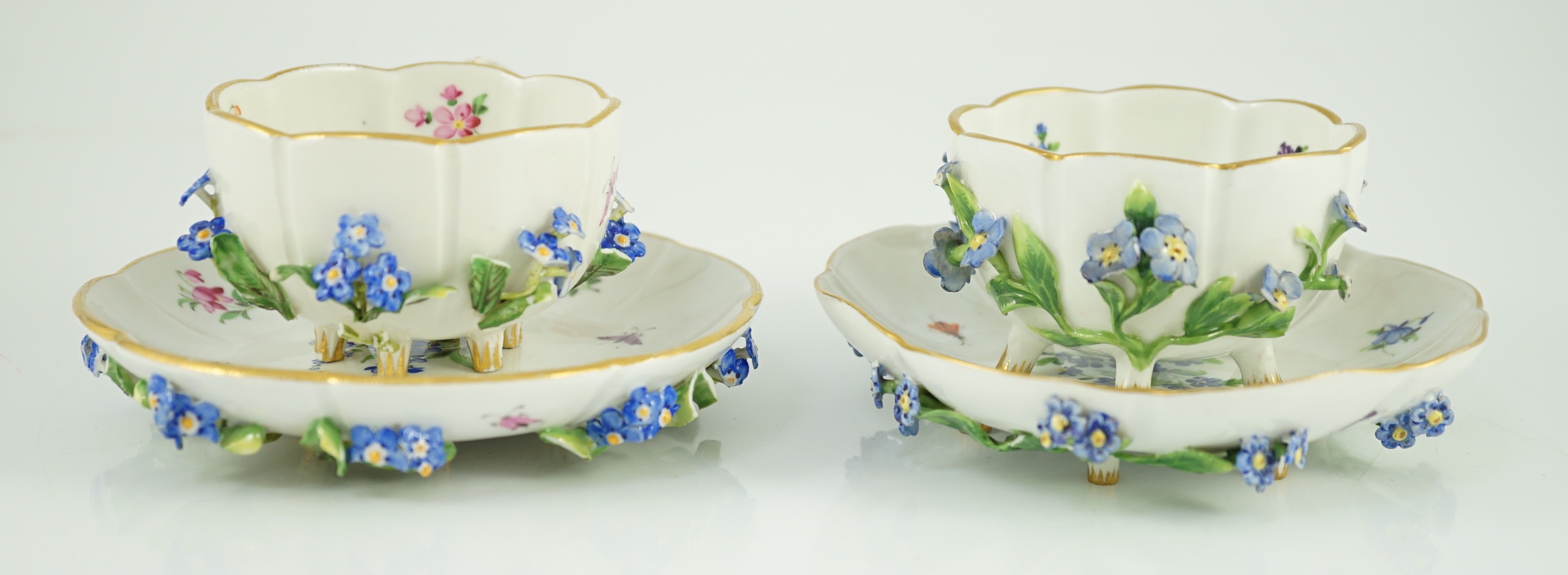 Two Meissen flower encrusted cups and saucers, 19th century, saucers 12cm wide, chips to flowers and leaves